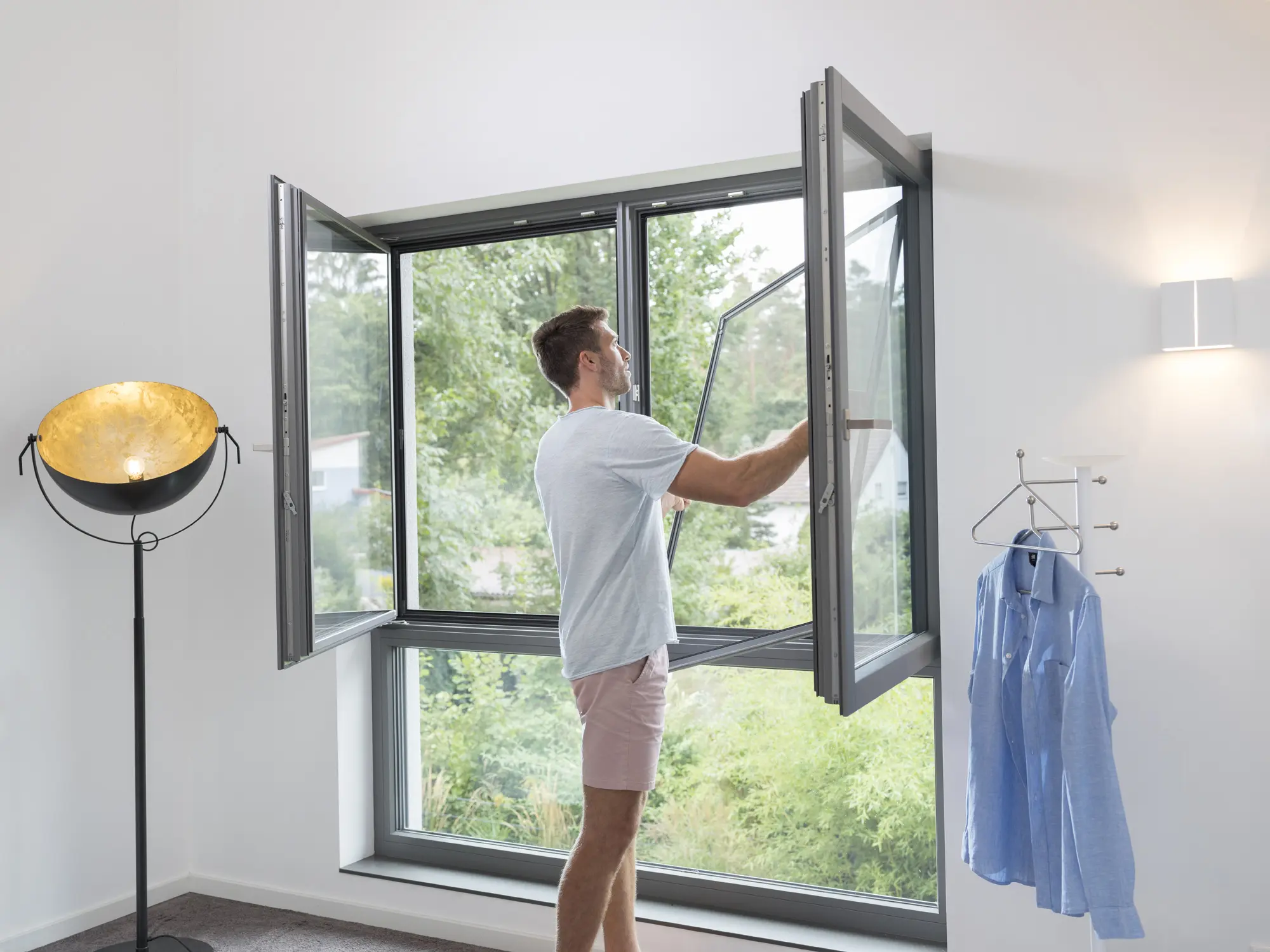 Mann setzt einen Insektenschutz-Spannrahmen in ein Fenster ein
